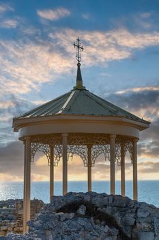 Yellow gazebo among the ruins of Chersonesos on the background of the blue sea. Sevastopol, Crimea