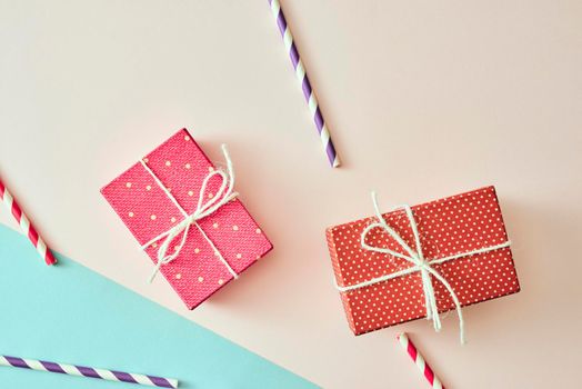 Two gift boxes wrapped in color purple and red polka dots paper on pink background.
