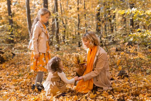 Young mother with her little daughter in an autumn park. Fall season, parenting and children concept