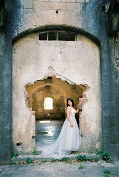 Bride stands near the dilapidated entrance of the old fortress. High quality photo