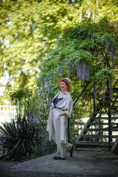 Thoughtful happy mature woman surrounded by chinese wisteria.