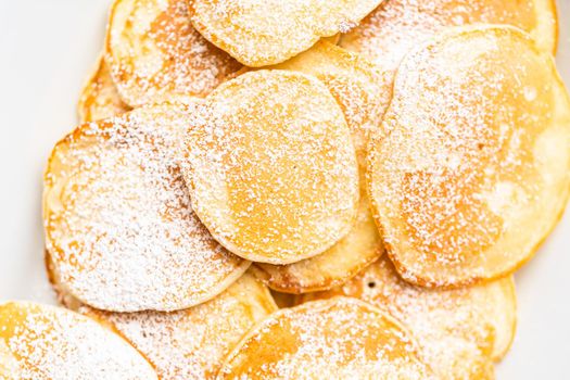 Flat lay. Freshly made small pancakes on a kefir base garnished with powdered sugar.