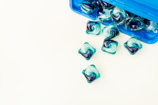 Blue-and-blue washing capsules are scattered on a white background. The process of washing clothes. Liquid washing gel