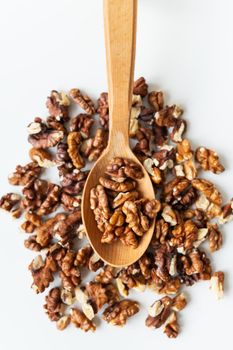 Wooden spoon with peeled walnuts. Separate on a white table. Delicious and healthy high-calorie food. Vertical photo