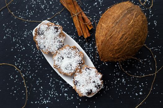 coconut muffins with chocolate on a black background and whole coconut