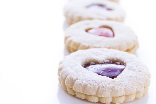 Linzer Torte cookies on white background with powdered sugar sprinkled on top.