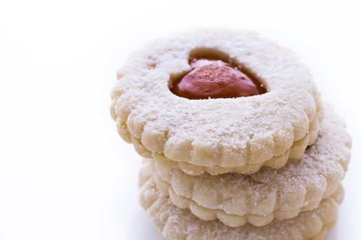 Linzer Torte cookies on white background with powdered sugar sprinkled on top.