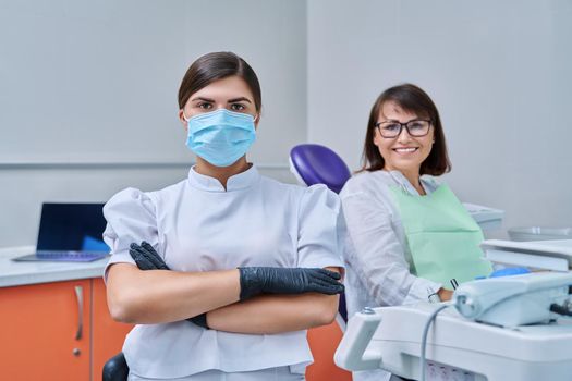 Portrait of young female doctor dentist looking at camera with mature woman patient sitting in dental chair. Dentistry, hygiene, treatment, medicine, dental health care concept