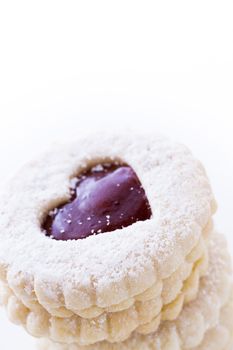 Linzer Torte cookies on white background with powdered sugar sprinkled on top.