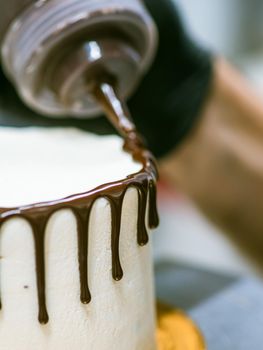 unrecognizable worker preparing a sweet dripping choco cake and berries