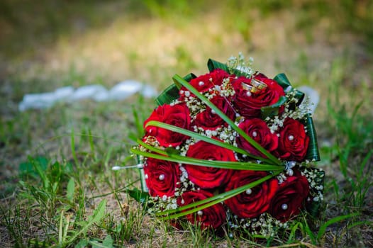 Bridal wedding bouquet of flowers. Wedding bouquet of red roses lying on a grass.