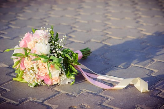 Bridal wedding bouquet of flowers. Wedding bouquet of yellow and white roses lies on the concrete floor.