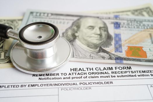 Health claim form with stethoscope and US dollar banknotes, insurance accident medical concept. 