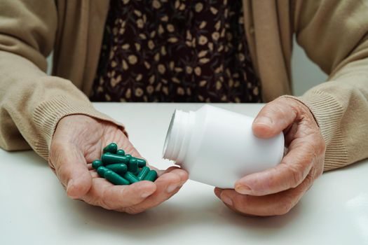 Asian elderly woman holding pill drug in hand, strong healthy medical concept.