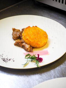 staff plating a modern second course meat decorated dish - line of prepared food for party