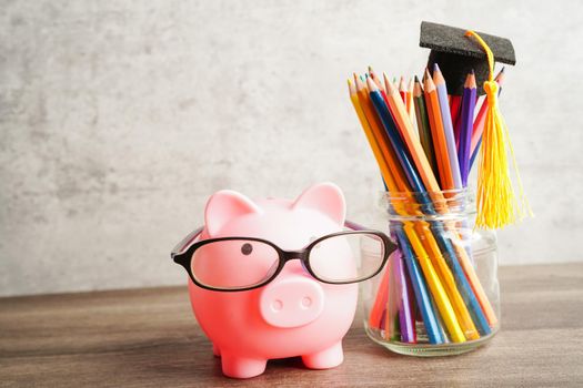 Pigging bank wearing eyeglass with coins and calculator saving bank education concept.