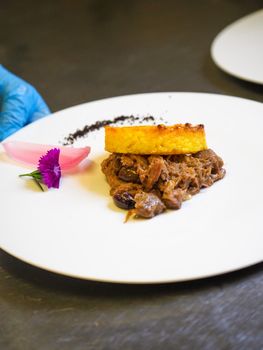 staff plating a modern second course meat decorated dish - line of prepared food for party