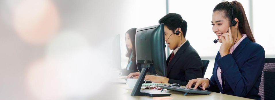 Business people wearing headset working in office in widen view to support remote customer or colleague. Call center, telemarketing, customer support agent provide service on telephone video call.