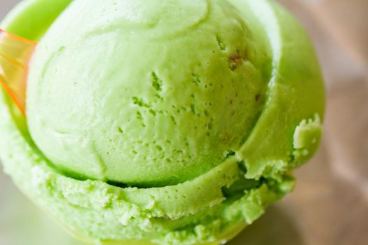 Green gelato in green plastic cup.