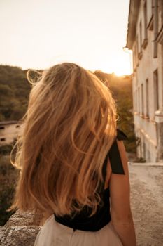 Blonde long hair, nature summer happy adult girl with long blond hair developing in the wind in nature. Dressed in a black top, white skirt