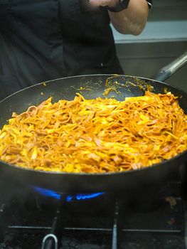 mixing pasta with sauce in a big professional used professional pan