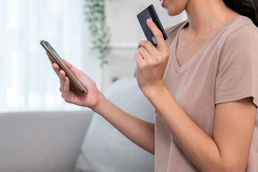 Contented young woman eagerly makes an online purchase using her smartphone. E-commerce business, online purchasing.