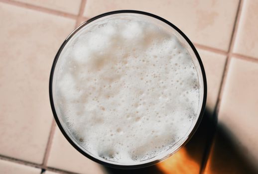 Glass of fresh lager beer with White fresh Foam on table. Beer foam top view. Bubble froth of beer.