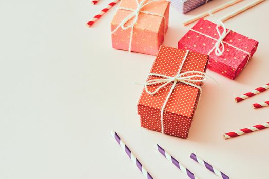 Flat lay composition with bright pink gift box, drink straws, ribbon and confetti. 
