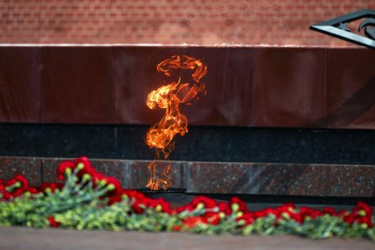Flowers by the Eternal Flame. Eternal Flame in the Kremlin. Guard of Honor at the tomb of the Unknown Soldier at the wall of Moscow Kremlin. 11.05.2022 Moscow, Russia.