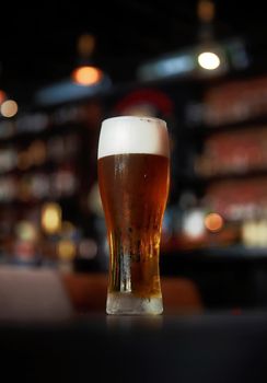 Fresh cold beer, glass of beer on a table in a bar on blurred bokeh background.