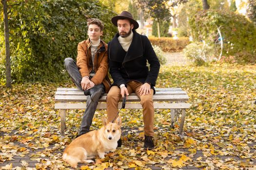 Father and son with a pet on a walk in the autumn park.