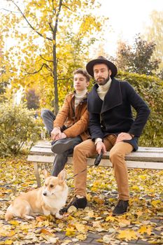 Father and son with a pet on a walk in the autumn park.