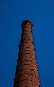 tall chimney old red bricks in an old factory. smoke stack An old brick chimney against a blue sky.