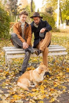 Father and son with a pet on a walk in the autumn park.