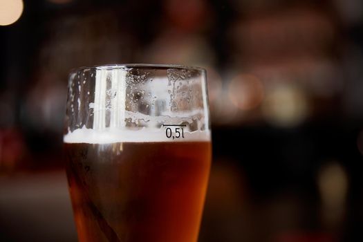 Glass of beer on a table in a bar on blurred bokeh background.