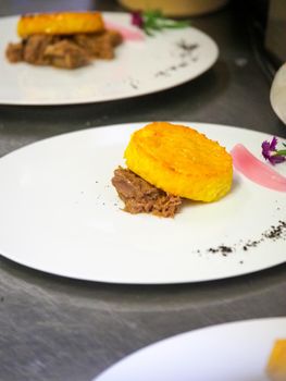 staff plating a modern second course meat decorated dish - line of prepared food for party
