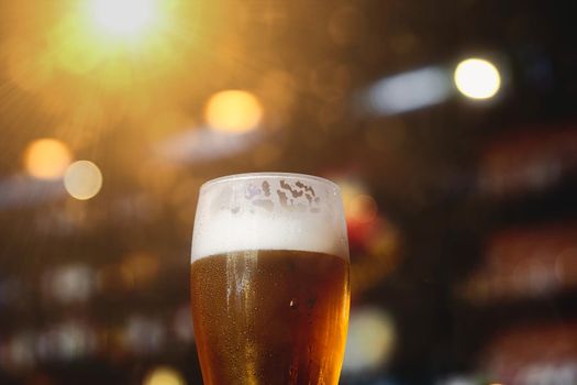 Glass of beer on a table in a bar on blurred bokeh background.