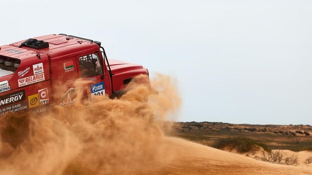 The rivalry between Kamaz and Maz at the rally. Sports truck KAMAZ gets over the difficult part of the route during the Rally raid in sand. THE GOLD OF KAGAN-2021. 26.04.2021 Astrakhan, Russia.