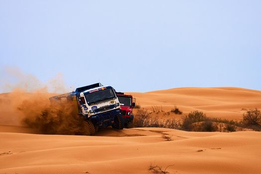 The rivalry between Kamaz and Maz at the rally. Sports truck KAMAZ gets over the difficult part of the route during the Rally raid in sand. THE GOLD OF KAGAN-2021. 26.04.2021 Astrakhan, Russia.