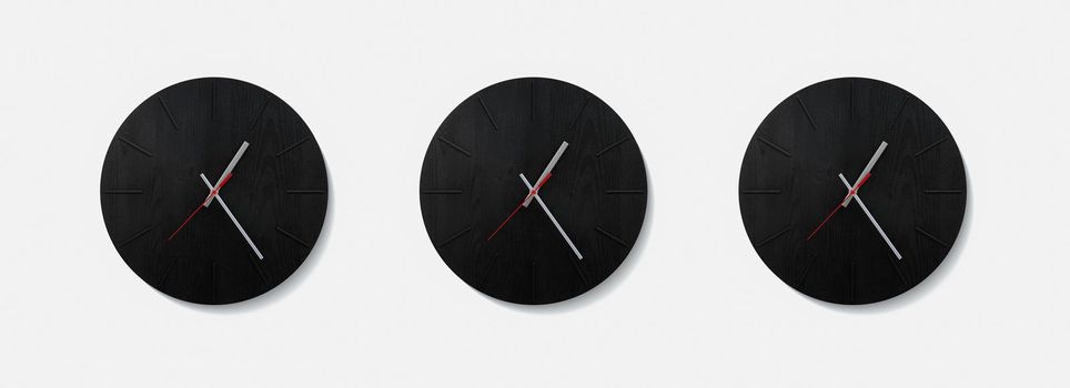 Stylish black round clock on a white wall. Time on the wall as an element of the interior. Simple modern round clock on white wall.