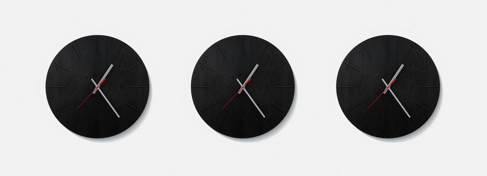 Stylish black round clock on a white wall. Time on the wall as an element of the interior. Simple modern round clock on white wall.