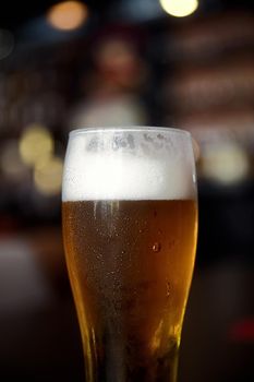 Glass of beer on a table in a bar on blurred bokeh background.