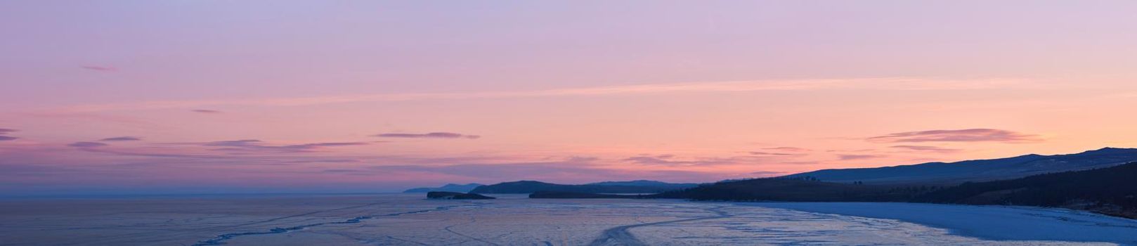 Frozen lake Baikal, at dawn. Winter landscape panorama