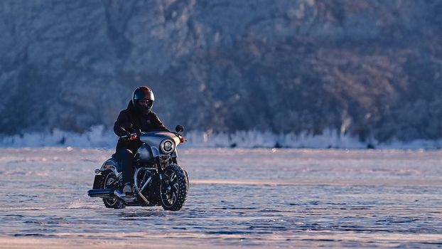 Biker riding on motorcycle Harley Davidson on a frozen lake. 03.08.2019 BAIKAL LAKE, OLKHON ISLAND, IRKUTSK REGION, RUSSIA