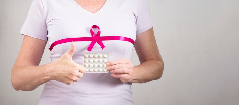 woman making heart sign with fingers on breast cancer protection symbol background. High quality photo