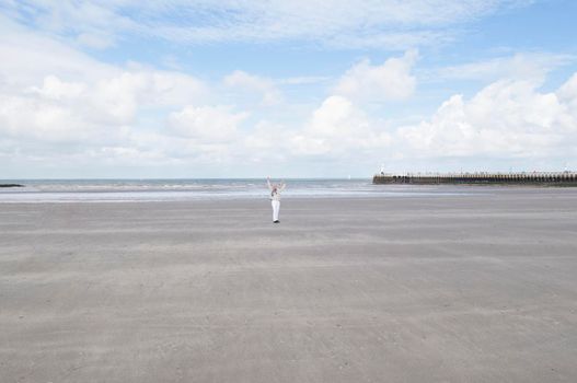 tiny woman runs open arms along the beach to the sea, High quality photo