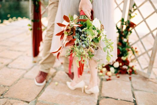 Bouquet of flowers tied with a ribbon in the bride hand. Cropped. High quality photo