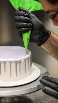 chef using using bag decorating a frosted icing cake
