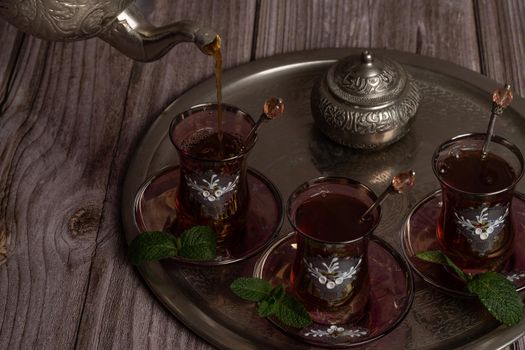 serving hot Moorish tea on a tray with glasses and pitcher on a wooden table