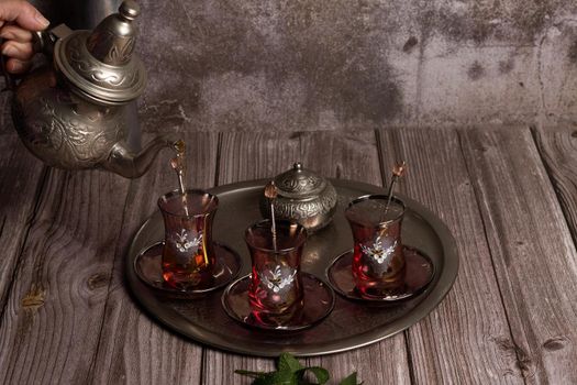 serving hot Moorish tea on a tray with glasses and pitcher on a wooden table